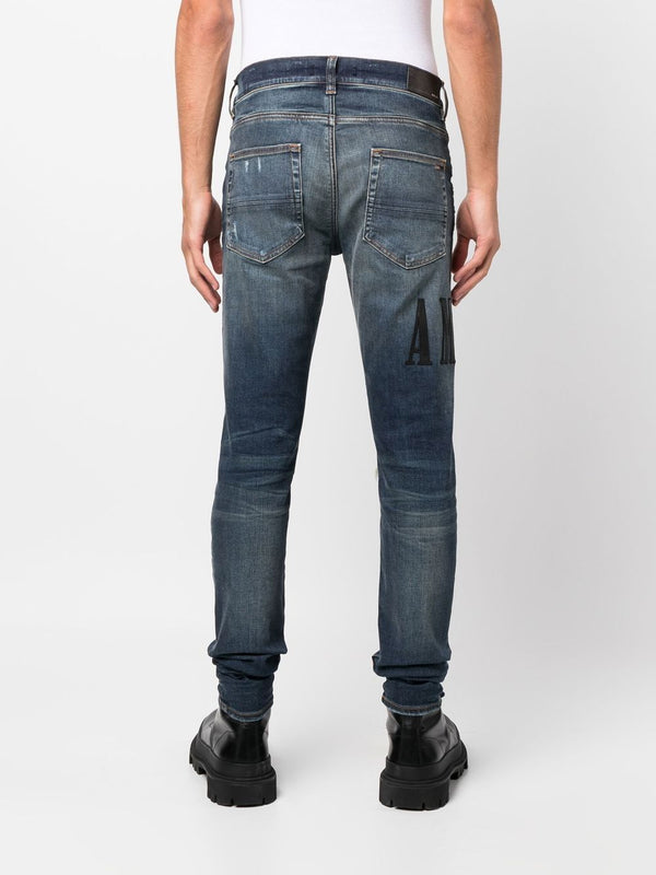 AMIRI distressed logo-print skinny jeans